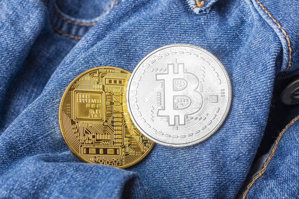 Two coins of silver and gold bitcoin on the background of jeans. Subject of Finance and Economy - Фото, изображение