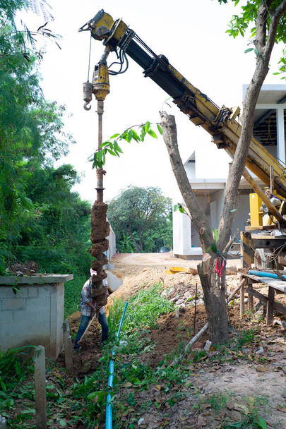 Landscape picture of workers drilling the soil ground by drilling machine. Drilling the hole for footing the reinforcement concrete poles. - Photo, Image