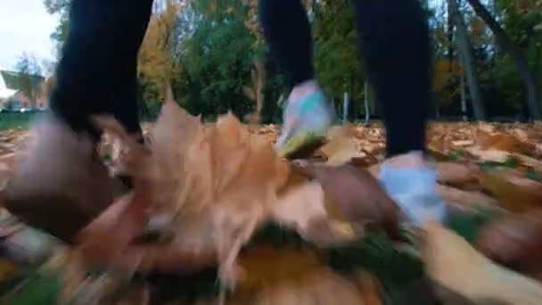 Nuoret hyväkuntoiset naiset pakenevat kameraa syyspuistossa. Vain jalat näkyvät
 - Materiaali, video
