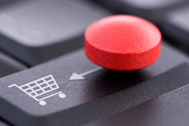 赤い錠剤とコンピューターのキーボード上のショッピングカート - 写真・画像