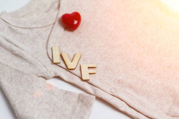 Baby clothes with test-tube and heart. Concept - IVF, in vitro fertilization. Waiting for baby, pregnant. - Photo, Image
