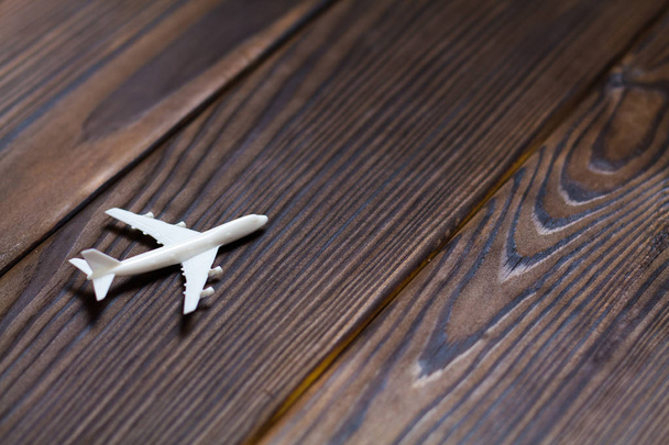 Miniatur-Spielzeugflugzeug auf dunklem Holzhintergrund. Reise mit dem Flugzeug. Geschäftsreisekonzept. - Foto, Bild