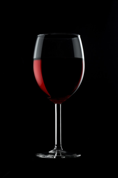 One glassed of red wine isolated on black background - Foto, afbeelding