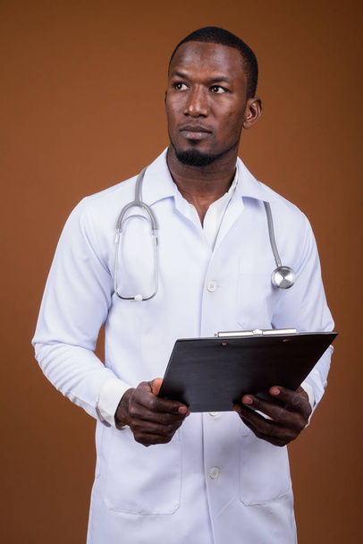 Handsome African man doctor against brown background - Фото, изображение