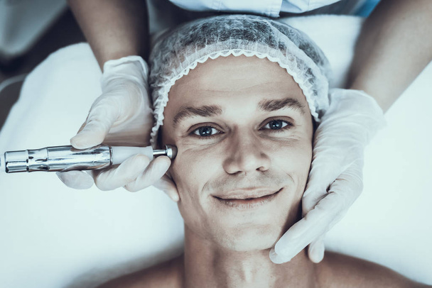 Young Man in Spa Salon for Laser Hair Removal. Guy in Beauty Salon. Modern Cosmetology. Proffesional Cosmetologist. Doctor with Laser Epilator. Men's Beauty Concept. Medical Equipment. - Fotoğraf, Görsel