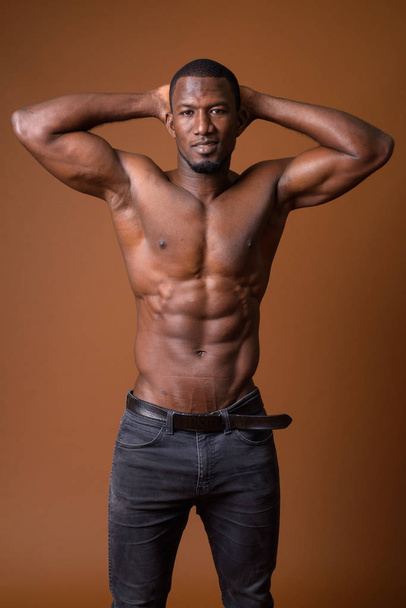 Красивый мускулистый африканский мужчина без рубашки на коричневом фоне
 - Фото, изображение