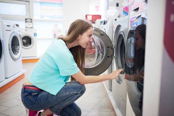 Young woman choosing washing machine in the appliance store - Foto, immagini