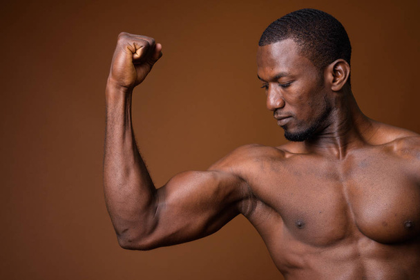 Handsome muscular African man shirtless against brown background - Photo, Image