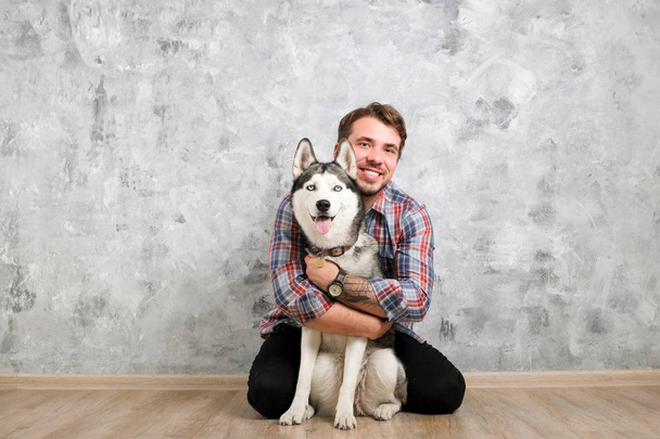 Young bearded man hanging out out with his husky dog. Hipster male wearing checkered flannel shirt and grey tank top spending quality time with four legged pet friend. Close up, copy space, background - Foto, Imagen