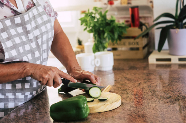 Ανώτερος γυναίκα κοπής λαχανικών στην κουζίνα στο σπίτι - Φωτογραφία, εικόνα