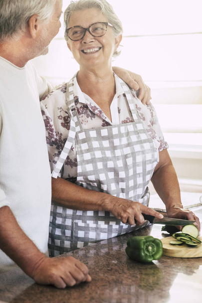 allegra coppia di anziani adulti a casa a lavorare insieme in cucina e tagliare verdure fresche di stagione
  - Foto, immagini
