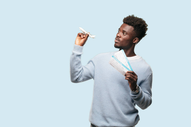 Young black man with boarding pass tickets and a plane model. Travel concept. - Foto, afbeelding