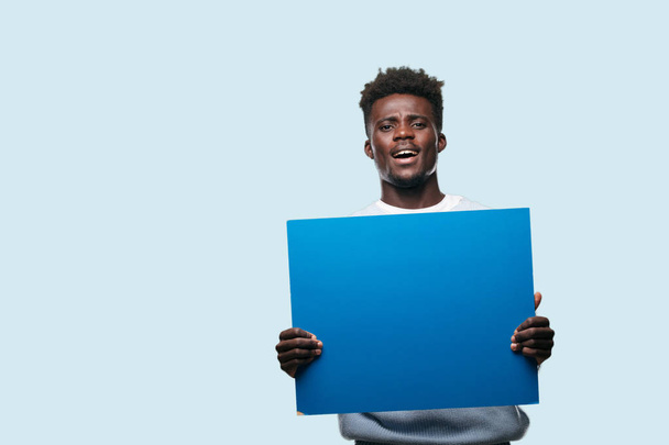 молодий чорний чоловік тримає порожній плакат, щоб розмістити вашу концепцію
 - Фото, зображення