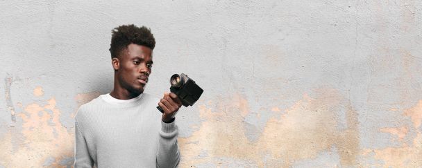 young black man recording with a super 8 vintage cinema camera - Fotoğraf, Görsel