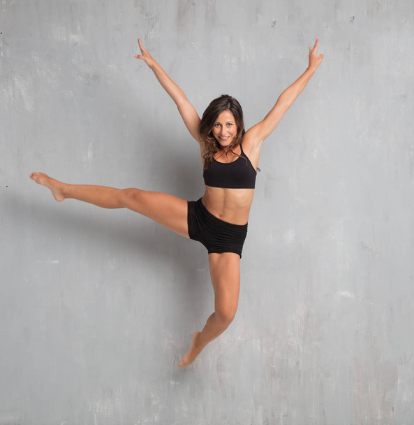 young pretty woman street dancer jumping against grunge wall background - Fotó, kép