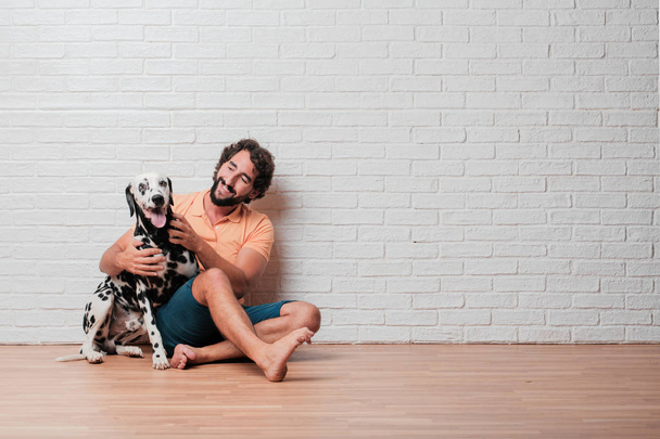 young bearded man with a dalmatian dog against white brick wall background - Photo, image
