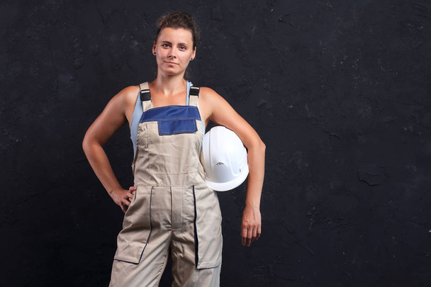 Female worker builder in uniform and white helmet. Portrait of pretty young woman engineer. - Zdjęcie, obraz