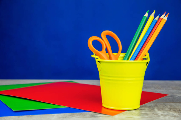 Colorful pencils and sheets of paper on white wooden desk and dark blue background - Foto, immagini