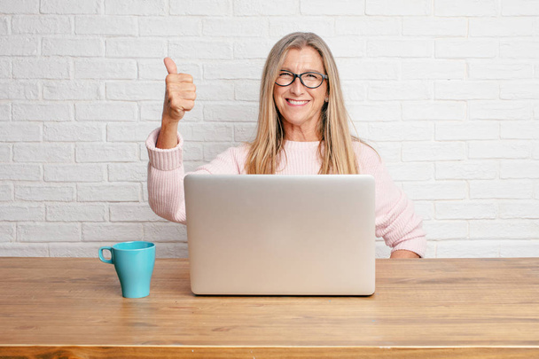 senior businesswoman with a satisfied, proud and happy look with thumbs up, signaling OK with one hand, sending a positive, "alright' message. - Foto, Imagem