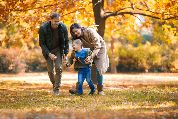 Молода сім'я розважається в осінньому парку зі своїм сином
. - Фото, зображення