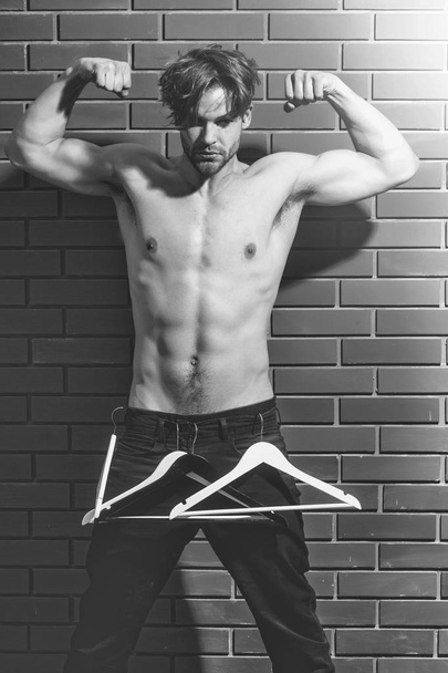 barbudo muscular macho hombre hipster con sexy cuerpo sostiene perchas
 - Foto, Imagen