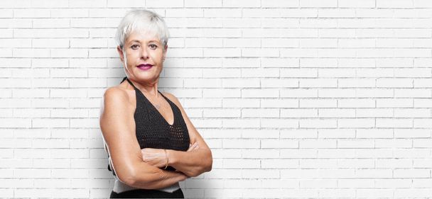 senior cool woman with a proud, happy and confident expression; accepting a challenge with arms crossed, smiling and sure of success, giving an "achiever" look. - Photo, Image