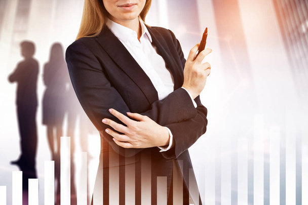 Unrecognizable smiling businesswoman with long blond hair holding a marker. Business team members silhouettes in background. Diagram interface in the foreground. Toned image double exposure - Photo, Image