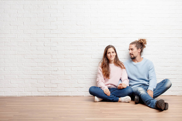 Happy young couple sitting on the floor of their new house. concept of love and moving house - Foto, afbeelding