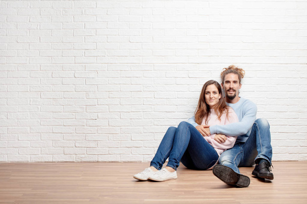Щаслива молода пара сидить на підлозі свого нового будинку. концепція любові і переїзду будинку
 - Фото, зображення