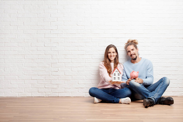 Happy young couple sitting on the floor of their new house. Concept of love and moving house. - Fotoğraf, Görsel