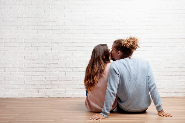 Happy young couple sitting on the floor of their new house. Concept of love and moving house. - Fotoğraf, Görsel