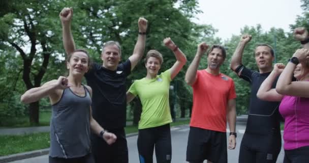 Gruppo di corridori visti da dietro, che fanno jogging insieme nel parco cittadino - Filmati, video