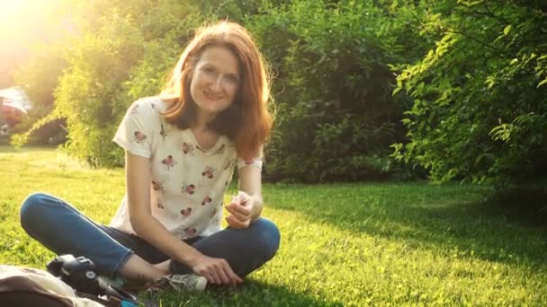 smiling girl sitting on a grass at the sunny summer evening - Video
