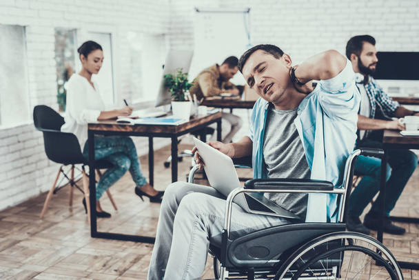 Tired Man in Glasses on Wheelchair in Office. Worker with Laptop. Disabled Young Man. Man on Wheelchair. Recovery and Healthcare Concepts. Teamwork in Office. Young Worker. Sitting Man. - Photo, Image