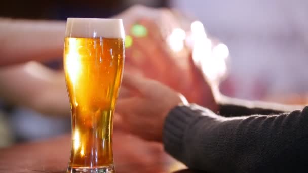 Guy friends drinking beer on the background. Full pint of beer in focus - Footage, Video