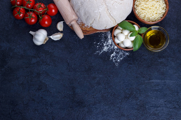 Πίτσα margherita στοιχείων ωμή ζύμη ντοματίνια βασιλικό ελαιόλαδο τυρί μοτσαρέλα σε σκούρο κουζινών πετρών πίνακα  - Φωτογραφία, εικόνα