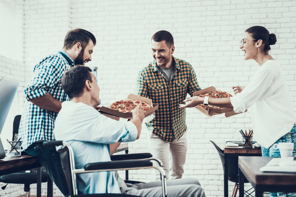 Young People Have Lunch with Pizza in Office. Teamwork in Office. Young Worker. Sitting Man. Box with Pizza. Young Girl in Glasses. Young Worker. Manager on Break. Man on Wheelchair. - Φωτογραφία, εικόνα