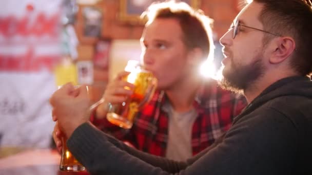 Dwóch facetów siedzieć w barze, popijając piwo - Materiał filmowy, wideo