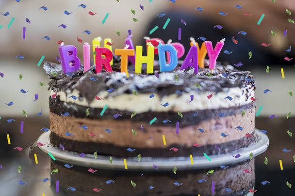 Chocolate birthday cake with confetti sprinkles and colorful candles greeting on the table at home - Foto, Bild