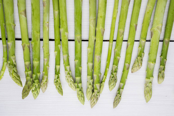 Fresh raw asparagus stems and buds on wooden table. Shot in the studio - Fotografie, Obrázek