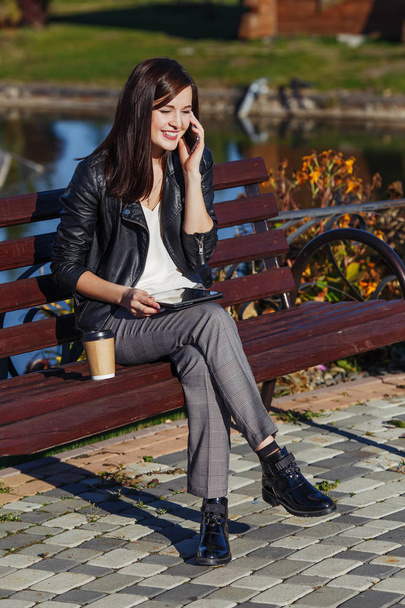 Belle femme caucasienne souriante avec téléphone mobile assis dans le parc
 - Photo, image