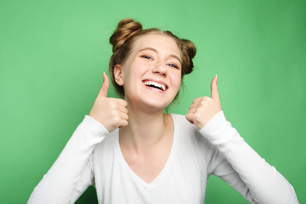 Happy young caucasian female making thumb up sign and smiling cheerfully, showing her support and respect to someone. Body language. - Foto, Imagen