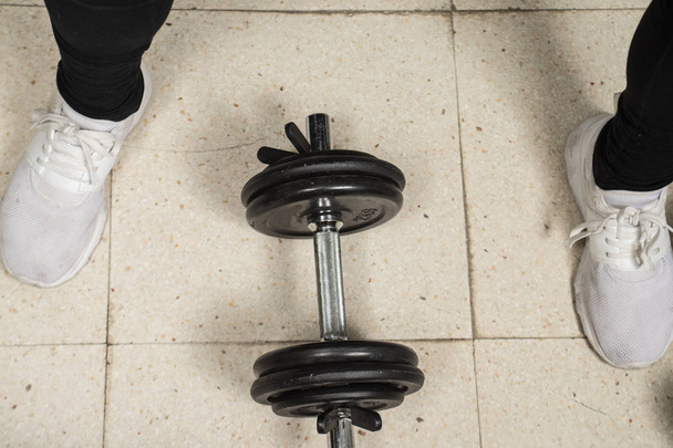 человек упражняется с гантелями, железный прут для упражнений с дисками разного веса
 - Фото, изображение