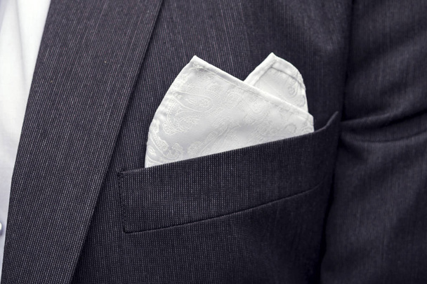 View to the male coat pocket with a fixed white square. Men's suit accessories. Wedding male guest's attire. Male wedding style. Formal dinner outfit for men. Elements of a suit. Pocket square folding - Photo, Image