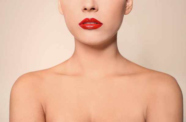 Beautiful young woman with red glossy lips on color background, closeup - Foto, afbeelding