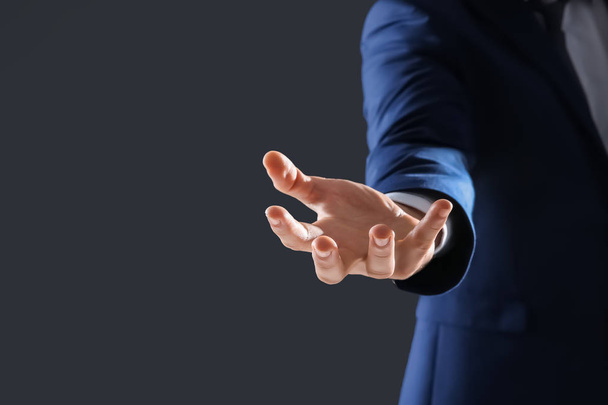 Businessman holding something in hand on dark background - Fotografie, Obrázek