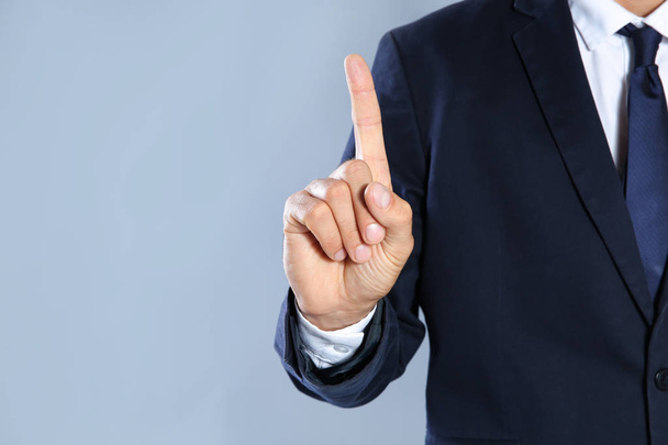 Businessman pointing on grey background, closeup view of hand with space for text - Foto, immagini