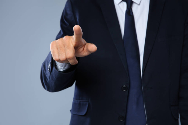 Businessman pointing on grey background, closeup of hand - Foto, Imagen