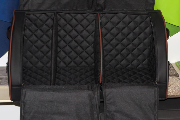 Das Innenteil der Tasche ist ein handgefertigter Organizer aus schwarzem und braunem Leder für den Kofferraum eines Autos zur Aufbewahrung von Sachen und Werkzeug in einem Schaufenster einer Werkstatt für Fahrzeuginnenausstattung. - Foto, Bild