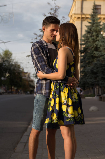 Paar, das sich vor dem Hintergrund der Stadt, der Straße, umarmt. urban romance.man streckt sich an die Lippen eines Mädchens, will sie küssen, Attraktion. Sexualität - Foto, Bild